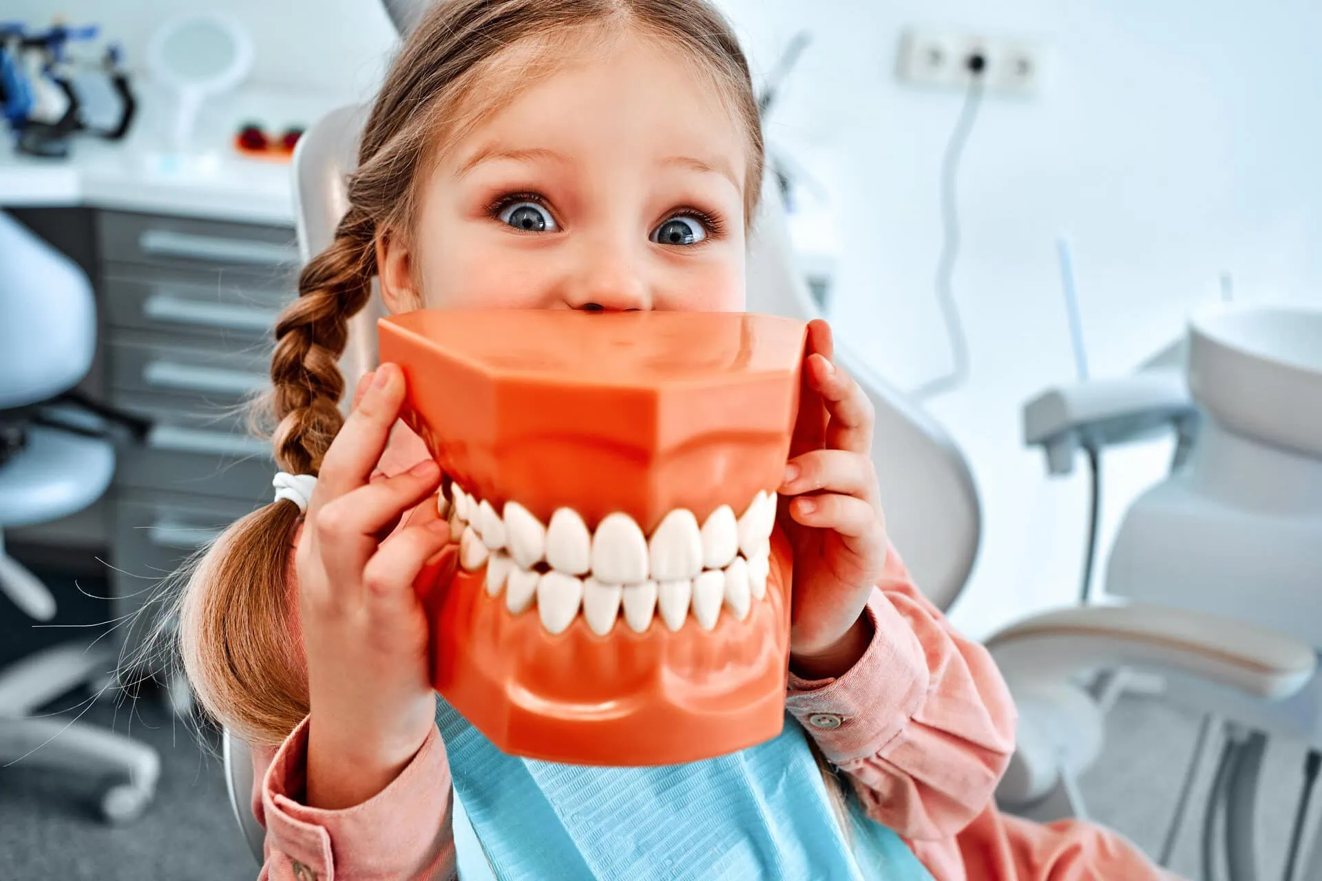 Girl holding a large model of teeth in front of her face